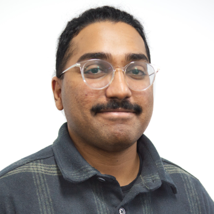 Image is of a smiling Bryan. He is wearing glasses, and a dark polo shirt.