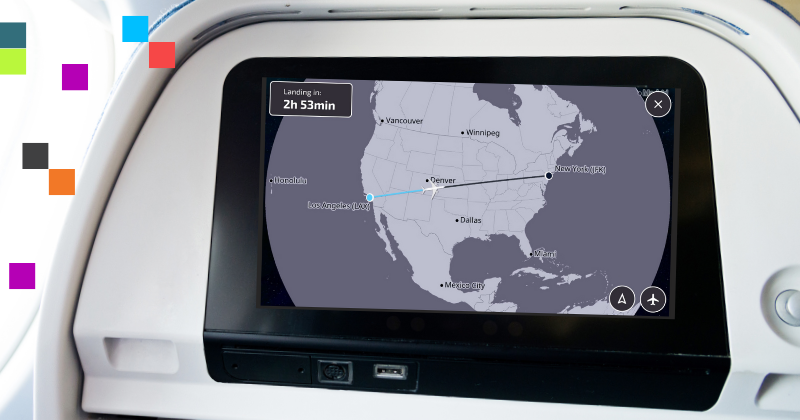 The photo shows the in-flight entertainment screen of an airplane, displaying a flight map. The map indicates the current flight path from New York (JFK) to Los Angeles (LAX) with a note that there are 2 hours and 53 minutes remaining until landing. The background of the screen shows a geographical map of the United States with major cities marked, such as Denver, Dallas, and Mexico City. There are colored squares (blue, red, black, orange) on the left side of the image, which may be part of the airline's branding or a design element.