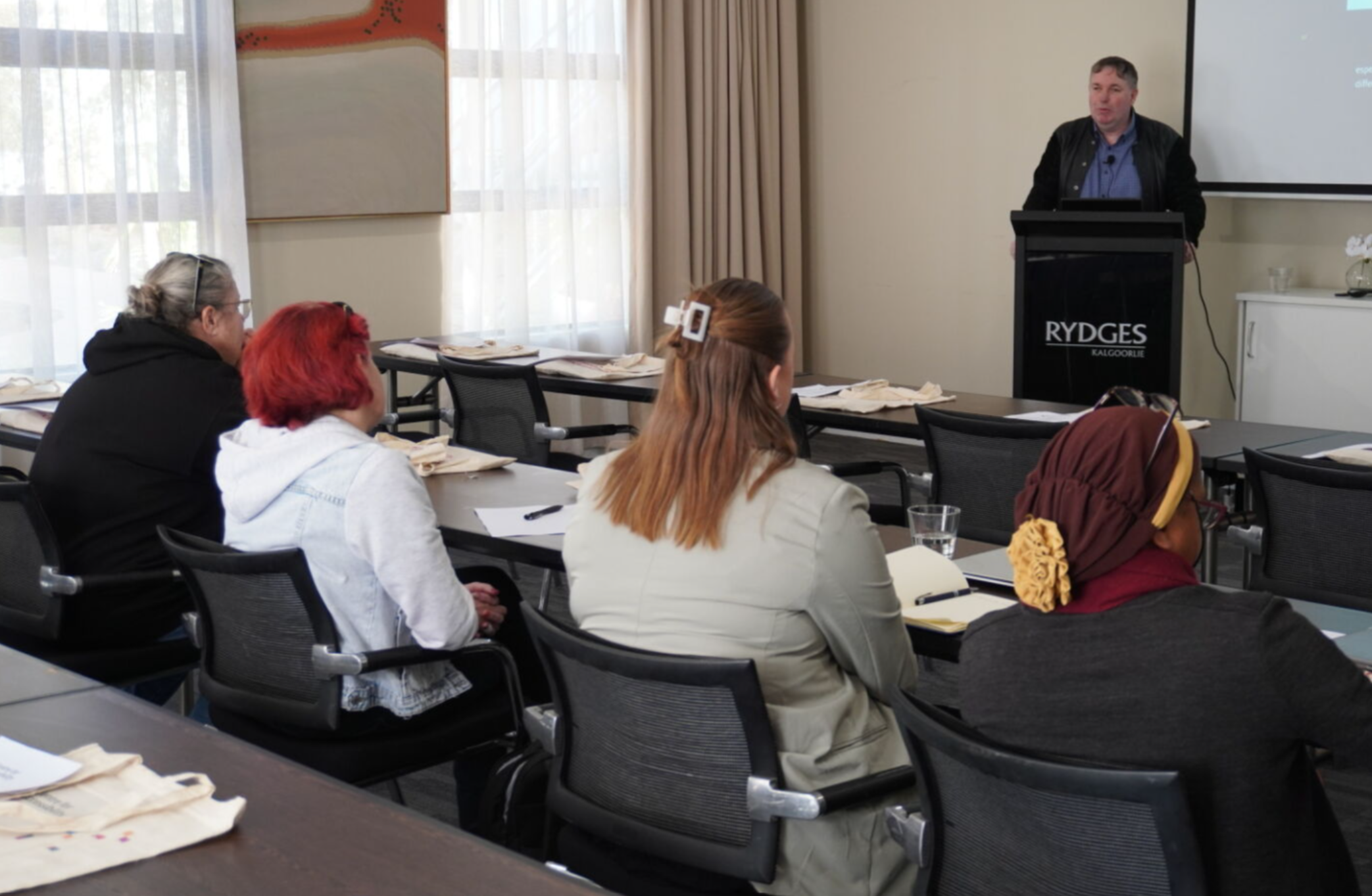 Image is of Dr. Scott Hollier presenting to an audience.