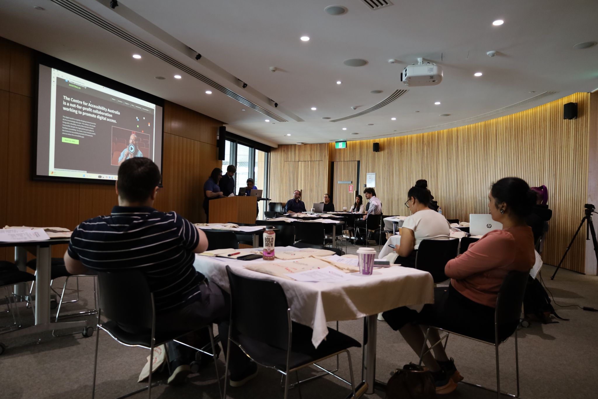 An audience watches the presentation.