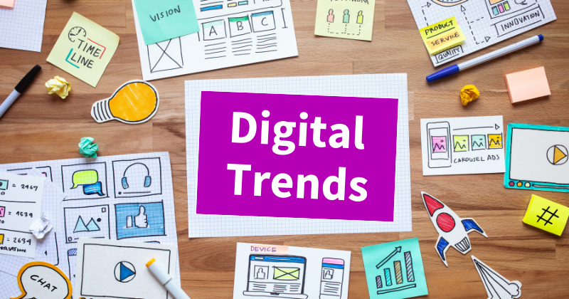 A desk with various coloured papers scattered about. The papers have graphs and computer symbols. The text says Digital Trends.