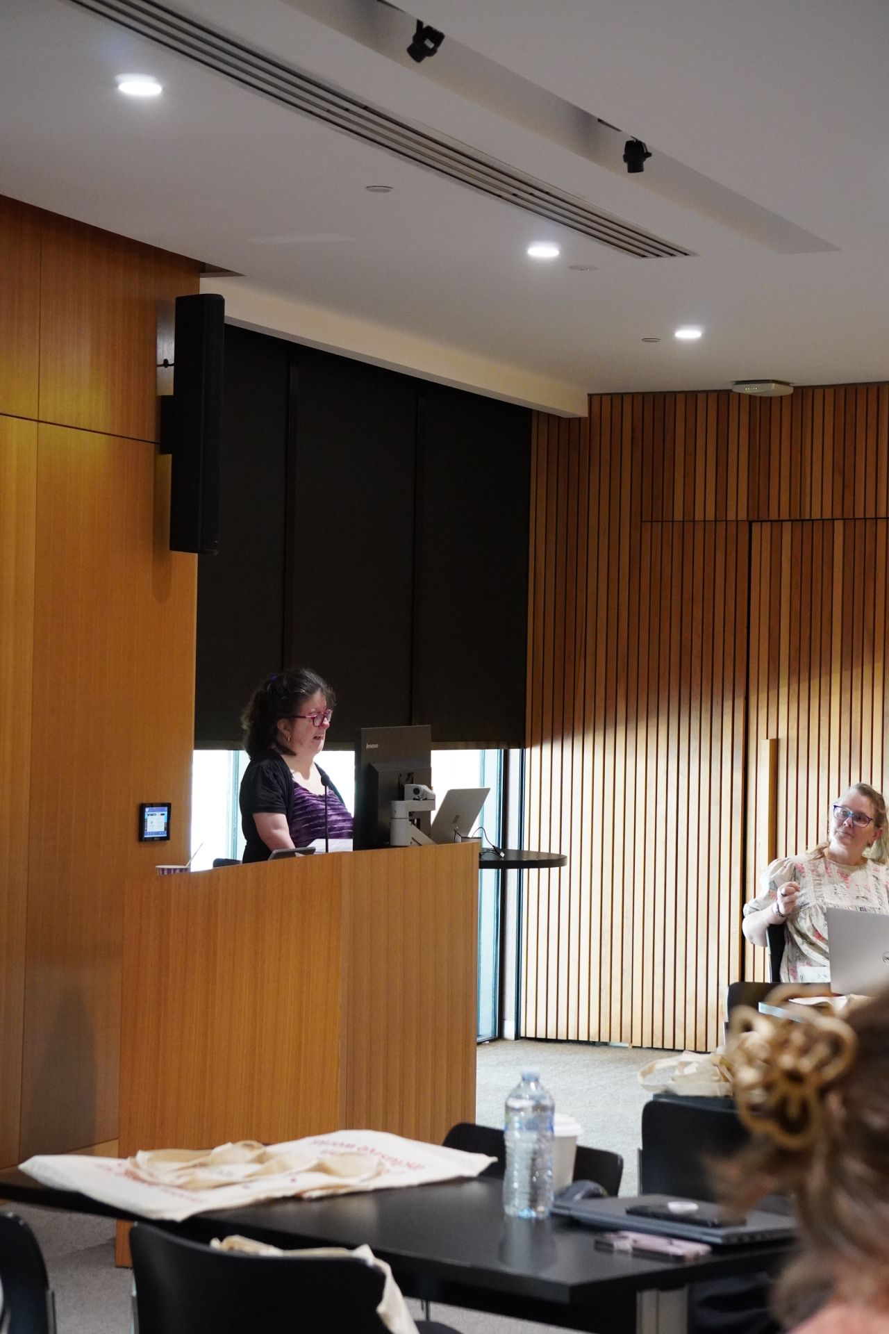 Laetitia stands at a podium, facing an audience.