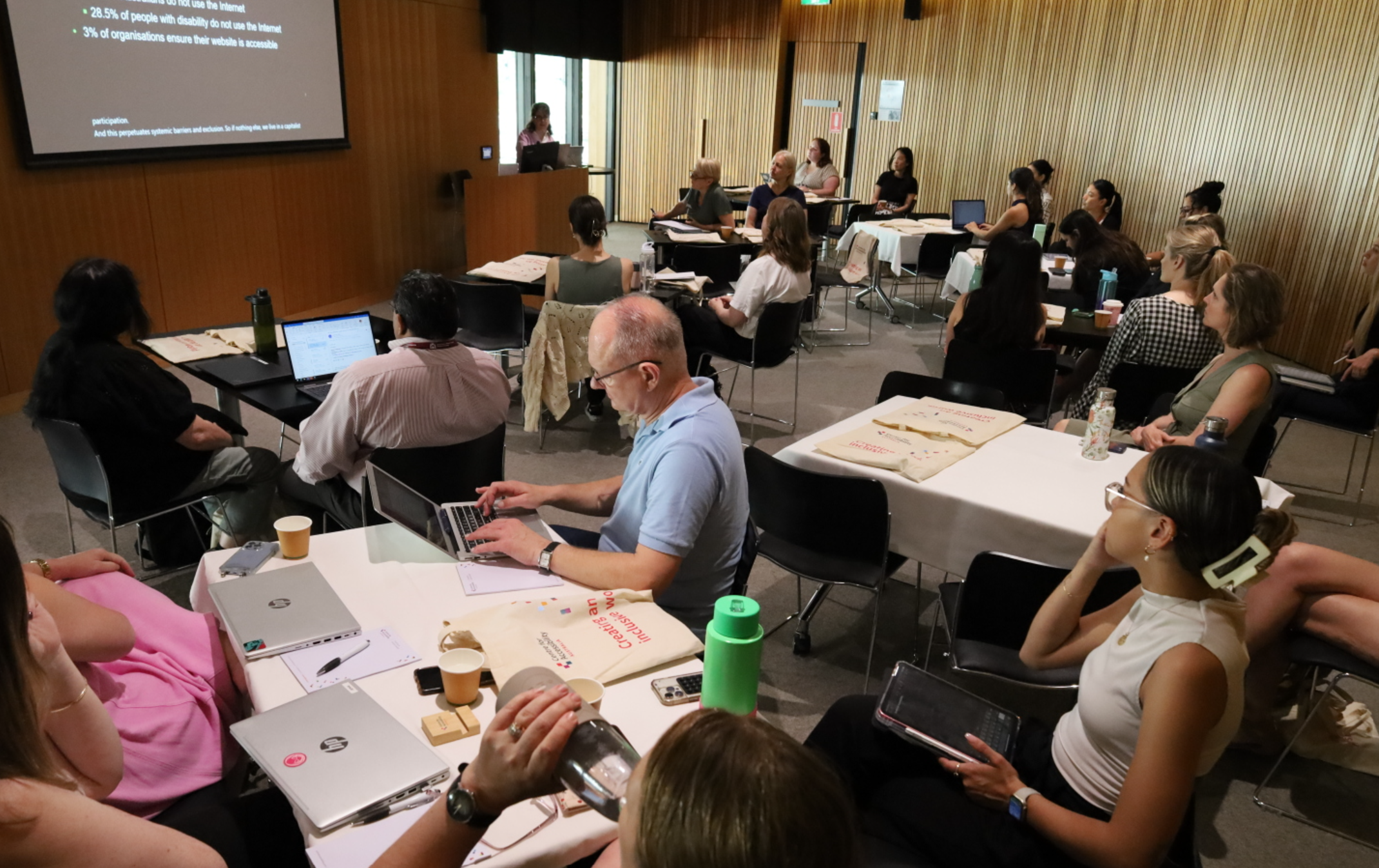 Photo of Laetitia presenting to an audience sitting at desks with their laptops.